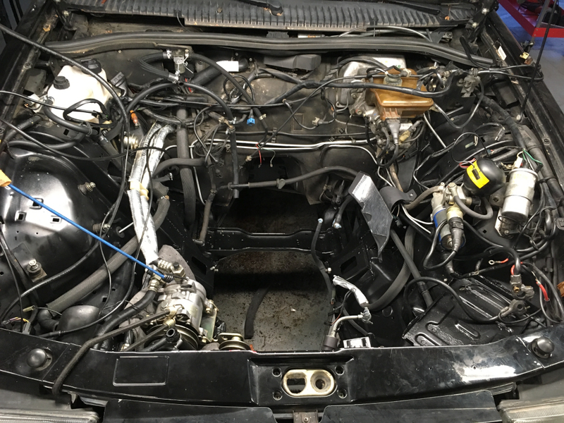 Blyth’s empty engine bay, featuring the newly silver heat-wrapped aircon lines to the left of the big hole.